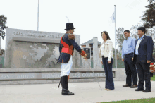 a man in a top hat shakes hands with a woman in front of a wall that says caidos dignidad los combatiente