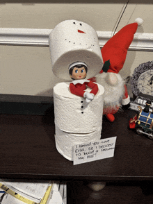 a elf on the shelf is sitting on a stack of toilet paper