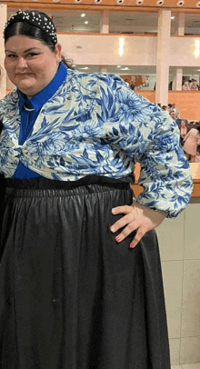 a woman wearing a blue and white floral shirt and black skirt