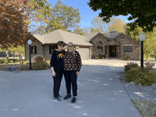 two people standing in front of a house with one wearing a sweatshirt that says iowa