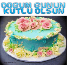 a blue cake with pink roses on it and the words dogum gunun kutlu olsun above it