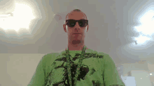 a man wearing sunglasses and a green shirt has a lanyard around his neck with circles