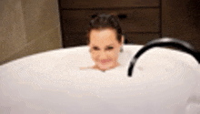 a woman is taking a bath in a tub filled with foam .