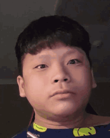 a young boy is making a funny face while wearing a blue shirt with a yellow banana on it .