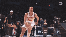 a basketball player is jumping in the air during a game with a state farm sign in the background .