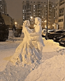 a snow sculpture of a bride and groom in a parking lot