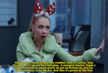 a woman wearing a reindeer headband and a green jacket is talking about christmas