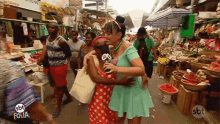 a woman in a green dress is hugging another woman in a market with sbt folia written on the bottom