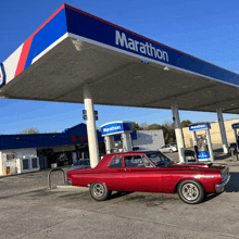 a red car is parked in front of a gas station called marathon