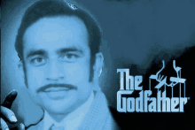 a man with glasses and a mustache is in front of a poster for the godfather