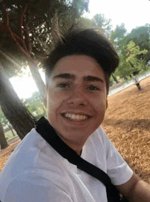 a young man in a white shirt and black tie is smiling for the camera .