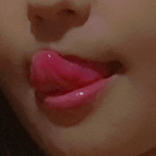 a close up of a woman 's lips with pink lipstick sticking out of them .