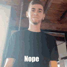 a young man in a black shirt is standing in front of a wooden ceiling and making a funny face .