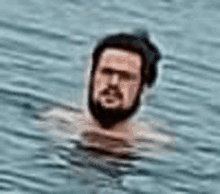 a man with a beard is swimming in the ocean with his head in the water .