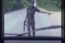 a blurry picture of a police officer standing on the side of a road holding a gun .