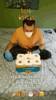 a man wearing a mask is sitting on a bed with a birthday cake made out of toilet paper rolls