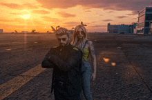 a man and a woman are standing on a runway with planes in the background