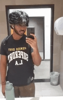 a man in a black shirt is taking a selfie in a bathroom .