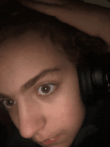 a close up of a person wearing headphones with their hand on their head