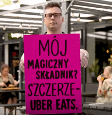 a man is holding a sign that says moj magiczny skladnik szczerze uber eats