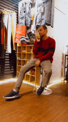 a man sits on a stool in front of a sign that says ' bar ' on it