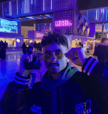 a man wearing sunglasses is standing in front of a music sign