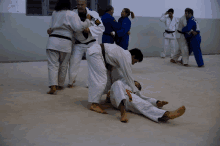 a group of people are practicing judo in a gym and one of them is wearing a black belt with the letter s on it