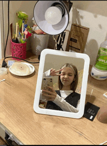 a girl taking a picture of herself in a mirror with a bottle of apple juice on the table