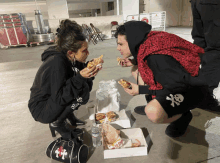 a man and a woman are eating a hamburger from a box