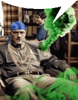 a man with a blue bandana on his head is sitting on a couch next to a green monster