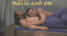 two men are laying next to each other on a bed with their arms around each other .