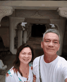 a man and a woman pose for a selfie in front of a building