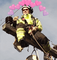 a man sitting on top of a pole with pink hearts coming out of his head