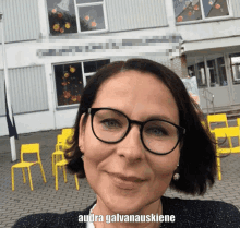 a woman wearing glasses is smiling in front of a building that says ' audra galvanauskienė ' on it