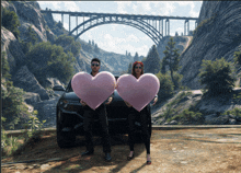 a man and a woman are holding pink hearts in front of a car