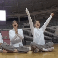 two girls sitting on the floor with their arms in the air and a sign that says ' a ' on it