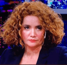 a woman with curly hair is wearing a black suit