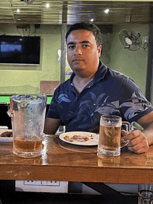 a man is sitting at a table with a pitcher of beer and a glass of beer