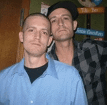 two men are posing for a picture with a tiki bar sign in the background