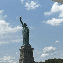 the statue of liberty stands tall against a cloudy sky