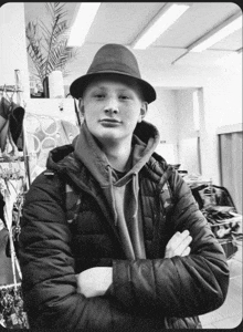 a black and white photo of a young man wearing a hat and a jacket