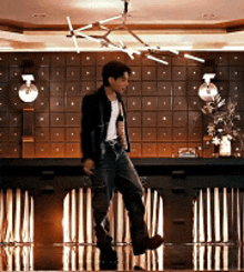 a man in a black jacket is dancing in a room .