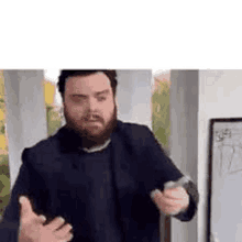 a man with a beard is standing in front of a whiteboard and holding a microphone .