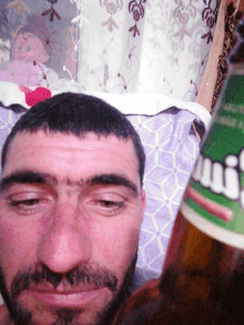 a man with a beard holds a bottle of mirinda