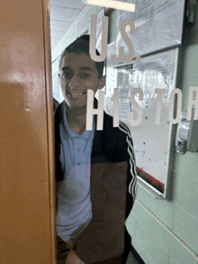 a boy stands in front of a door that says " us history "