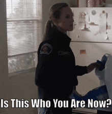 a woman in a police uniform is standing in front of a refrigerator with the words " is this who you are now " above her