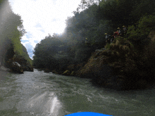 a group of people in yellow helmets are standing on a rock overlooking a river