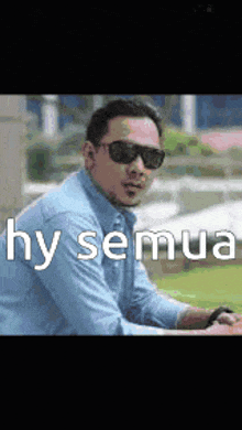 a man wearing sunglasses and a blue shirt is sitting on a bench with the words hy semua written above him .