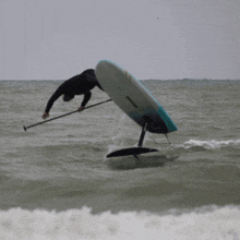 a man is riding a surfboard in the ocean with a yellow sticker on it that says ' foil ' on it