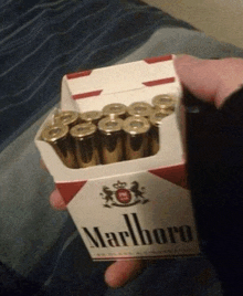 a person is holding a pack of marlboro cigarettes filled with bullets